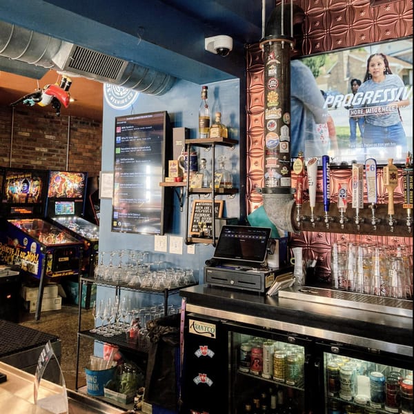 Interior of Tennessee Avenue Beer Hall, featuring a bar with beer taps, pinball machines, and a TV.