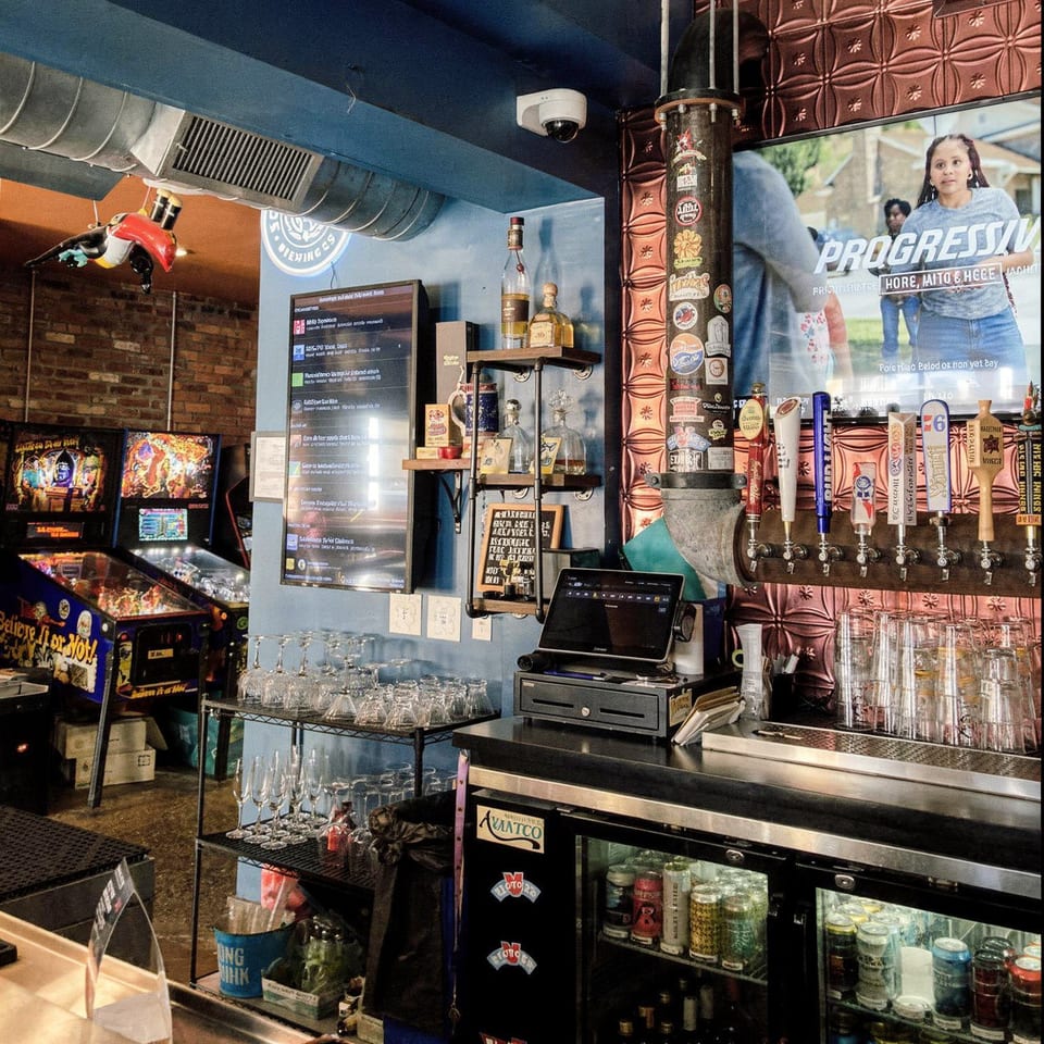 Interior of Tennessee Avenue Beer Hall, featuring a bar with beer taps, pinball machines, and a TV.