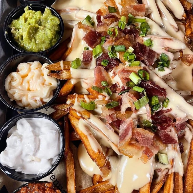 Loaded fries with cheese sauce, bacon, and green onions, served with guacamole, aioli, and sour cream.