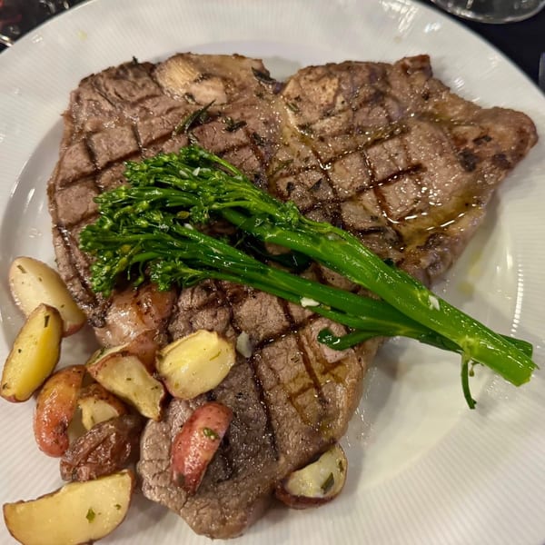 Grilled steak with broccolini and roasted potatoes on a white plate at Tennessee Avenue Beer Hall.