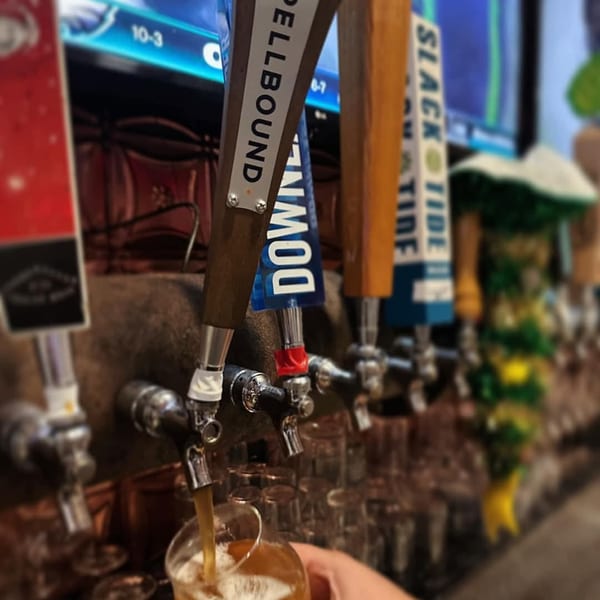 A hand holding a glass under a beer tap, filling it with golden beer at Tennessee Avenue Beer Hall.