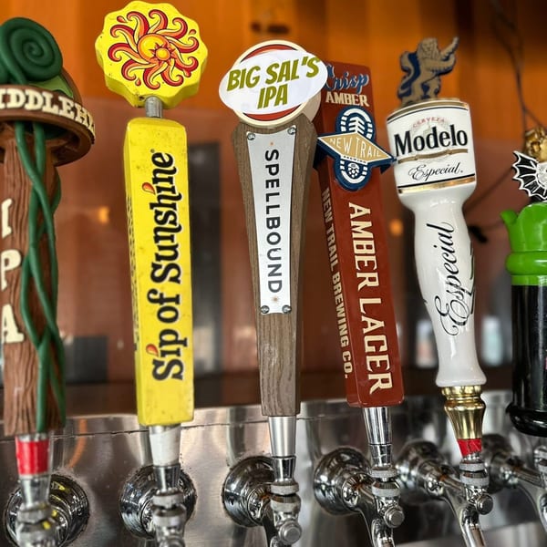 Close-up of five beer taps with various colorful handles, including Modelo Especial and Sip of Sunshine.