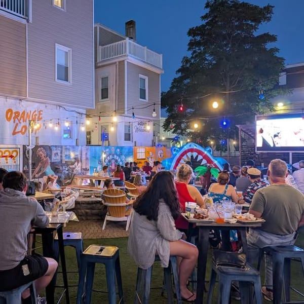 Patrons enjoying food and drinks at outdoor tables under string lights at Tennessee Avenue Beer Hall.